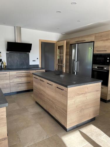 une cuisine avec des armoires en bois et un comptoir noir dans l'établissement Gîte Chez Les Perrin, à Tendon