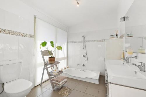 a white bathroom with a toilet and a sink at Perfect Beach getaway in Narrabeen