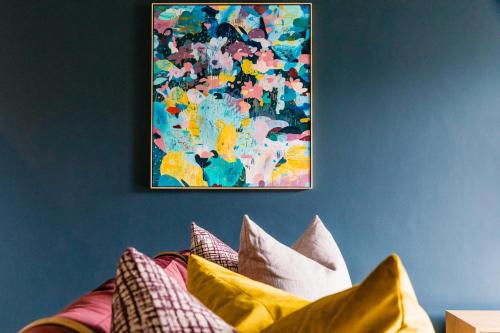 a painting hanging on a wall above a bed with pillows at Latitude Aparthotel by Totalstay in Cape Town
