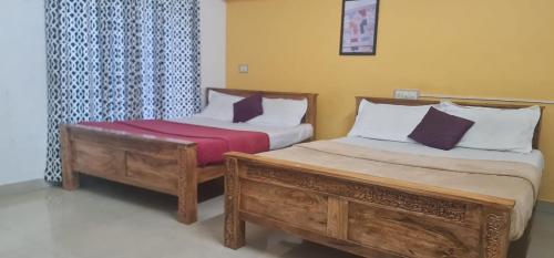 two beds sitting next to each other in a room at Madikeri residency in Madikeri