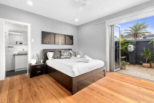 a bedroom with a large bed and a balcony at Beachside Magic - Footsteps to the Beach in Narrabeen