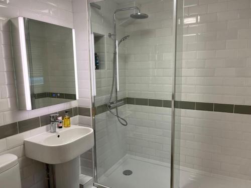 y baño con ducha, lavabo y puerta de ducha acristalada. en South Downs Cottage With Views, en Poynings