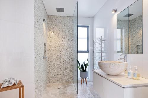 a bathroom with a sink and a glass shower at Curley Sunrise - Oceanfront in Curl Curl