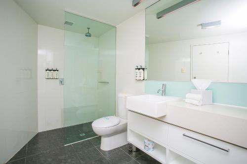 a white bathroom with a toilet and a sink at East Perth Suites Hotel in Perth