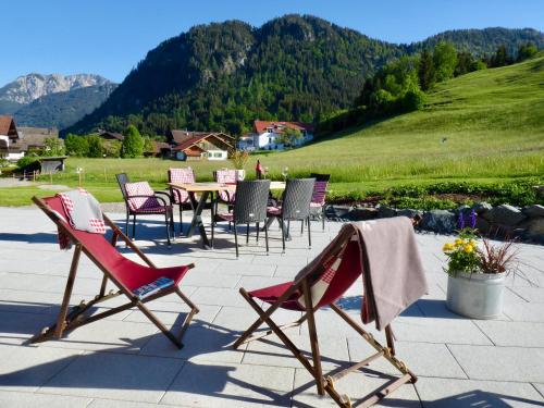 a group of lawn chairs and a table with mountains in the background at Gästehaus Sonnenplatzerl in Pfronten