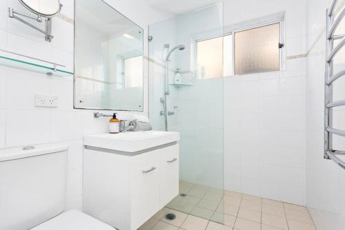 a white bathroom with a sink and a shower at Beachfront Magic Unbeatable Location in Sydney
