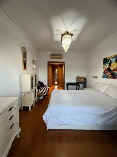 a bedroom with a large white bed and a chandelier at Private room with view in Estoril