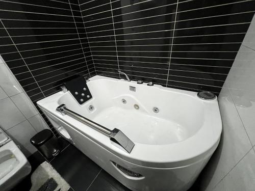 La salle de bains est pourvue d'une baignoire blanche et de carrelage noir. dans l'établissement Sunrise Apartment in Prishtina, Kosovo, à Pristina
