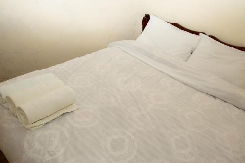 a white bed with a folded towel on it at Hilda's place in Embu