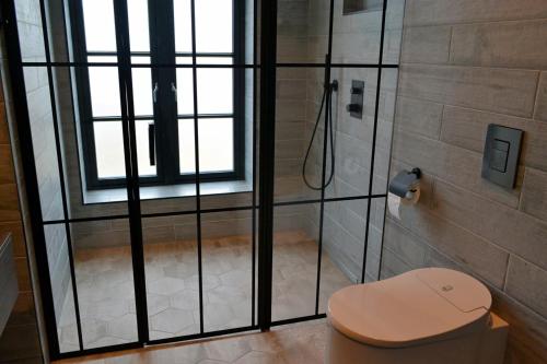 a bathroom with a shower with a toilet and a window at Andenes Suitehotel in Andenes