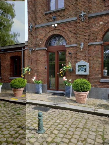 a brick building with potted plants in front of it at Appartement dans un bâtiment historique in Thorembais-Saint-Trond
