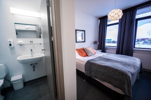 een slaapkamer met een bed, een wastafel en een badkamer bij The Northern Comfort Inn in Ólafsfjörður