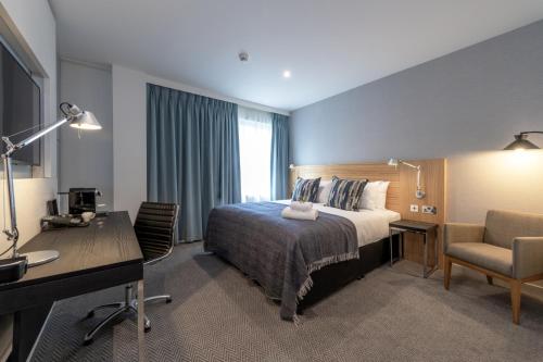 a hotel room with a bed and a desk and a chair at Apex City of Edinburgh Hotel in Edinburgh