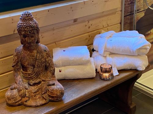 a statue of a woman sitting on a bench with towels at Holzhaus Onkel Fritz mit Sauna und Whirlwanne in Esch
