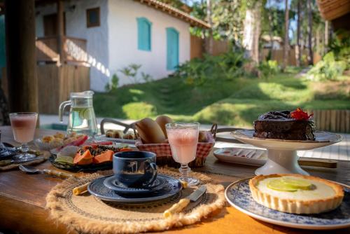 uma mesa de madeira com comida e bebidas em Villa Mediterrâneo Trancoso em Trancoso