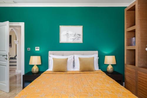 a green bedroom with a bed and two lamps at La Villa Dubrovnik in Trsteno