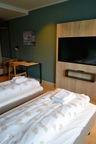 two beds in a room with a flat screen tv at Andenes Suitehotel in Andenes