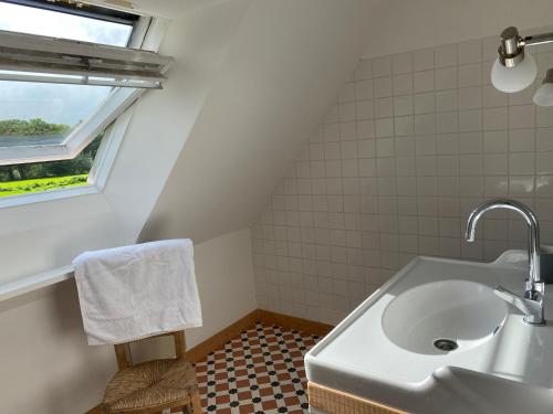 une salle de bain blanche avec un lavabo et une fenêtre dans l'établissement Maison authentique - mer et campagne - 6 couchages ou 12 couchages, à Pleumeur-Bodou