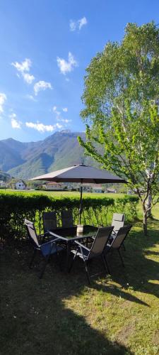 a table and chairs with an umbrella on the grass at Apartma Soča Oasis in Srpenica