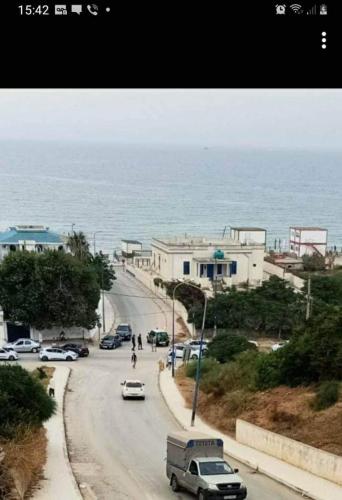 een straat met auto's die over een weg langs de oceaan rijden bij Yakoub in Skikda