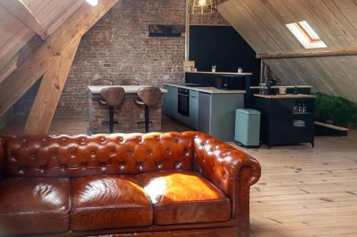 a brown leather couch in a room with a kitchen at Le Street in Calais