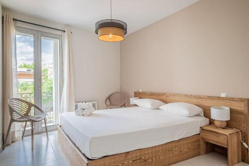une chambre avec un lit blanc et une grande fenêtre dans l'établissement La Maison Mediterranéenne, T4, Terrasse, clim, pkg, à Montpellier