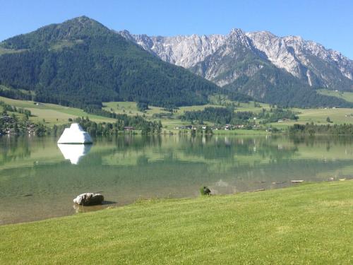 a lake with a white object in the water with mountains at Landhaus Schwentner in Kössen