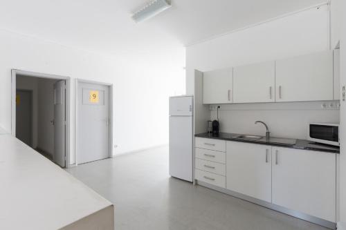 a white kitchen with white cabinets and a sink at Smile4Porto Guest House in Porto