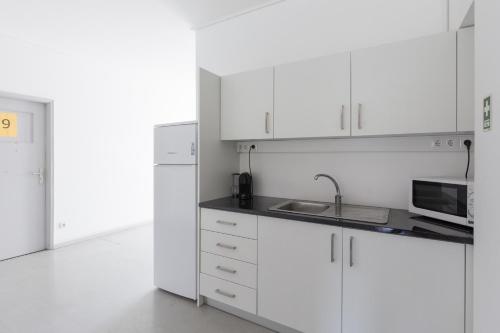 uma cozinha branca com um lavatório e um micro-ondas em Smile4Porto Guest House no Porto