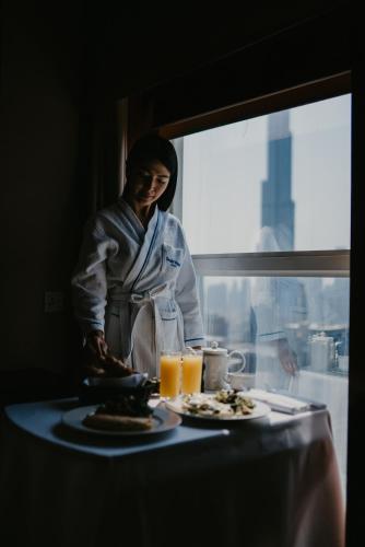 a woman standing next to a table with a plate of food at Dusit Thani Dubai in Dubai