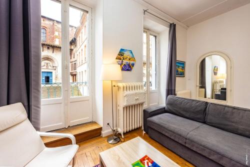 un salon avec un canapé et une fenêtre dans l'établissement Appartement Secteur Cathédrale - Hypercentre - Albi, à Albi