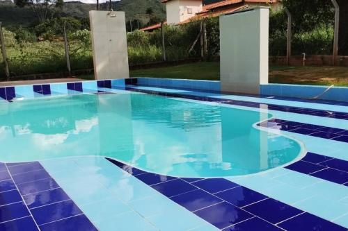 a swimming pool with blue and white tile on the floor at Sítio Paraíso Serrano em Igarapé in Igarapé