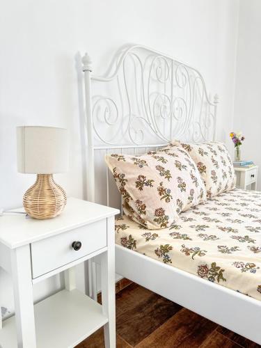 a white bed with a white nightstand and a lamp at Апартамент за гости Лена Златоград in Zlatograd