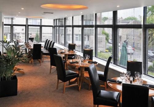 um restaurante com mesas e cadeiras e janelas grandes em Westberry Hotel em Bodmin