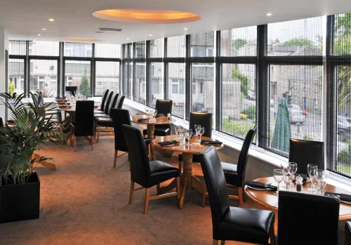 un restaurante con mesas, sillas y ventanas grandes en Westberry Hotel, en Bodmin