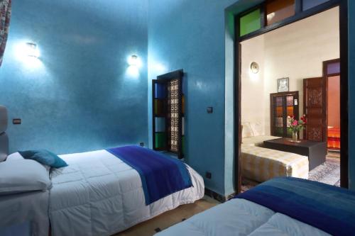 a bedroom with two beds and a blue wall at Riad Dwiriyat My Teib in Marrakech