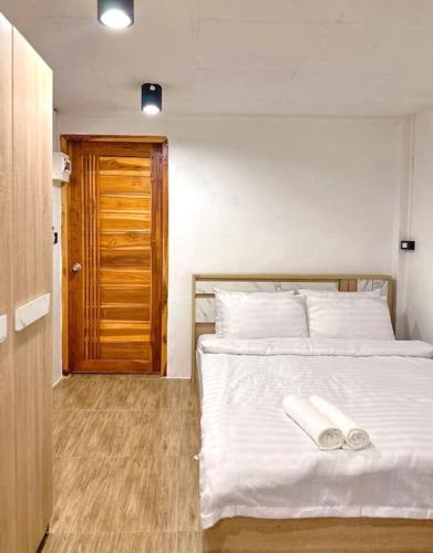 a bedroom with a white bed and a wooden door at Chubby 5 Room 4 in Ban Bang Bamru