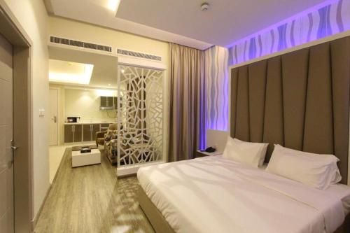 1 dormitorio con 1 cama blanca grande con iluminación púrpura en حياة روز للشقق الفندقية, en Riad