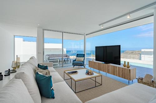 Una sala de estar con un sofá blanco y un televisor. en Villa Estándar 1 - Casangular by Upper, en Adeje