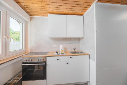 a kitchen with white cabinets and a sink and a window at Monteurwohnungen in Göppingen 04-07 in Göppingen