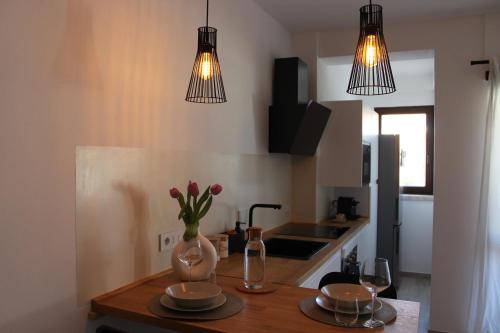 Una cocina con dos luces y una mesa con flores en un jarrón. en Olbia Apartment, en Olbia