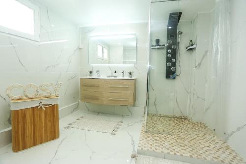 ein weißes Badezimmer mit einem Waschbecken und einem Spiegel in der Unterkunft CasaLova in Épinay-sur-Seine