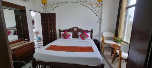 a bedroom with a large bed with pink pillows at Hotel Darbargarh A Unit of Khamma Ghani A Boutique Hotel in Udaipur