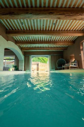 a swimming pool with a wooden ceiling and blue water at Mas Loisonville - Demeure d'exception & Spa en Drôme Provençale in Grillon