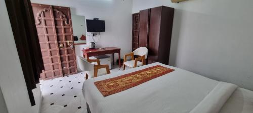 a bedroom with a bed and a desk and a television at Hotel Darbargarh A Unit of Khamma Ghani A Boutique Hotel in Udaipur