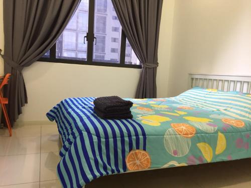 a bedroom with a bed with a colorful comforter and a window at Icon Residenz Icon City, Petaling Jaya by De Harlequins Guesthouse in Petaling Jaya