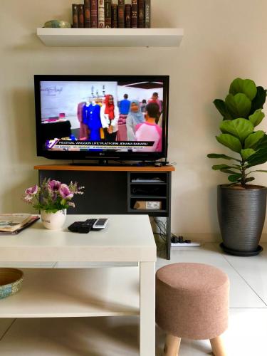 a living room with a television and a table with a chair at Icon Residenz Icon City, Petaling Jaya by De Harlequins Guesthouse in Petaling Jaya