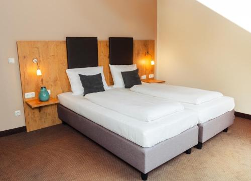 a bedroom with a large bed with two pillows at Hotel am Hachinger Bach by Blattl in Neubiberg