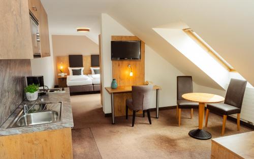 a kitchen and living room with a sink and a table at Hotel am Hachinger Bach by Blattl in Neubiberg