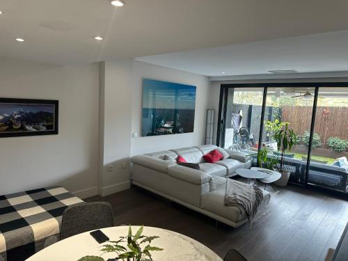 uma sala de estar com um sofá e uma mesa em Oasis Familiar, casa con jardín con ubicación Ideal em Alcobendas